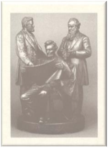 A black and white photo of a sculpture depicting three men, one seated and two standing.
