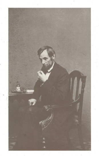 Vintage photo of a man seated at a table, holding a pipe.